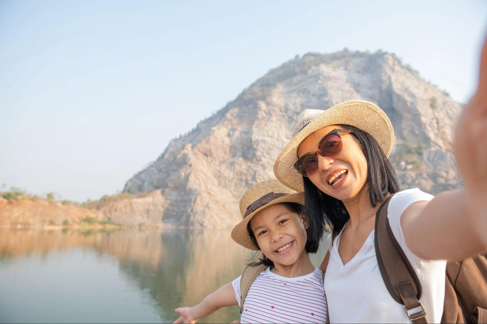 mother and daughter standing near lake