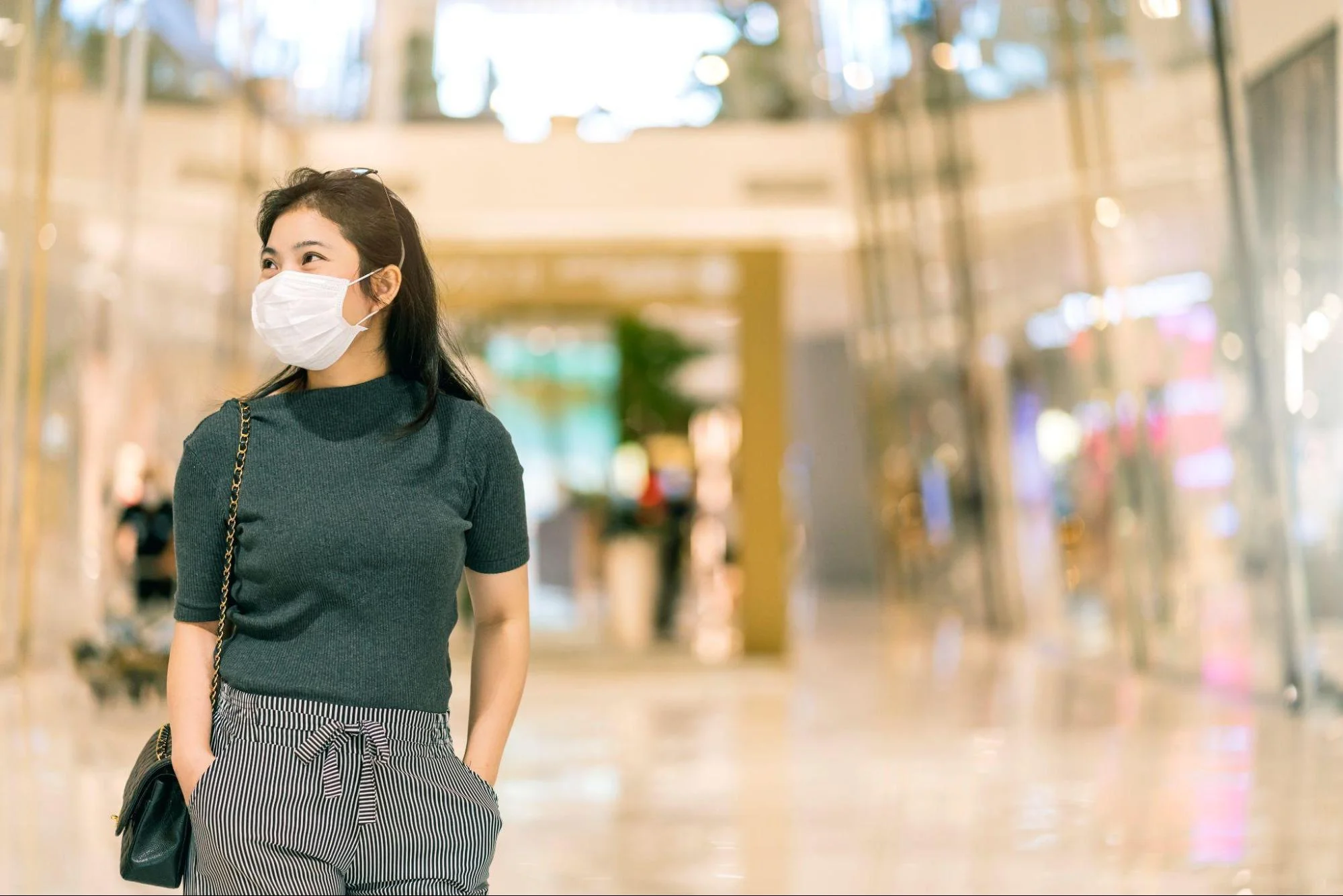 female wearing facial mask walking in department store mall